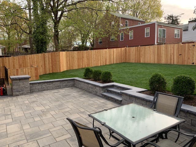 Completed stone patio, lawn, fencing, and foundation planting project
